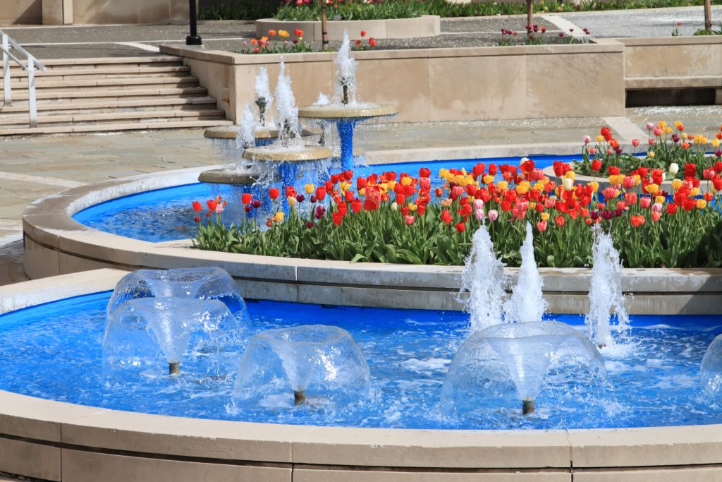 A fountain with red and orange flowers located in downtown Peoria IL